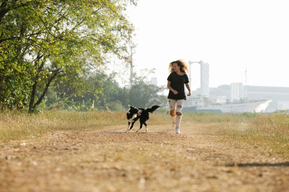 河川敷を愛犬と楽しそうに走る女性